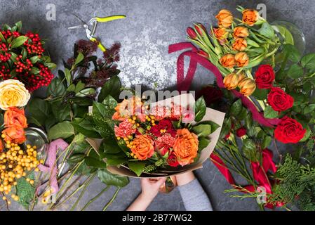 Das Konzept der Geschenke und Blumensträuße für den 8. März und den Muttertag. Blumenhändler schafft einen Blumenstrauß in einem Blumenladen. Stockfoto