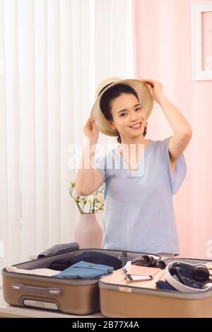 Junge Frauen wählen Hut mit Kleidung und Koffer. Vorbereitung auf den Sommerurlaub Stockfoto