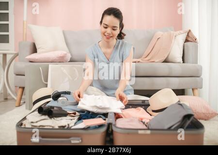 Schöne Frau packt ihren Koffer im Wohnzimmer Stockfoto