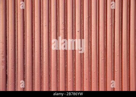 Gewelltes Wellblech mit senkrechten Balken, die mit dunkelroter Farbe lackiert sind und als Hintergrund nützlich sind Stockfoto