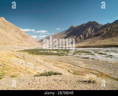 Fluss und Tal von Spiti, die im Sommer von hohen Gipfeln und der Rätsellinie der Berge des Himalaya unter blauem Himmel in der Nähe von Kaza, Himachal Pradesh, Indianapolis, flankiert werden Stockfoto