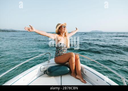 Junge Frau, die auf dem Deck eines Bootes am Meer genießt Stockfoto