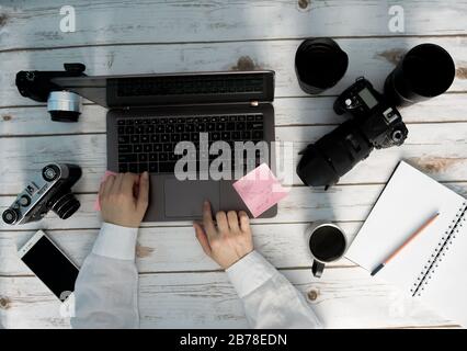 Arbeitsbereich des Fotografen - Laptop und verschiedene Kameras Stockfoto