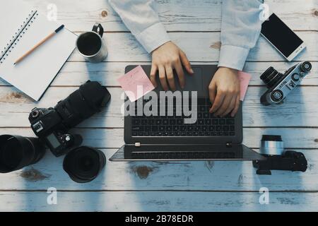 Arbeitsbereich des Fotografen - Laptop und verschiedene Kameras Stockfoto