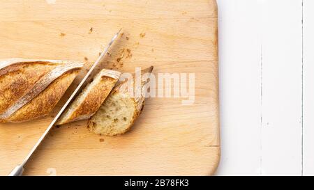 Schneiden Sie französische Baguettes, Brot mit einem Messer auf einem Holzschneidebrett. Stockfoto