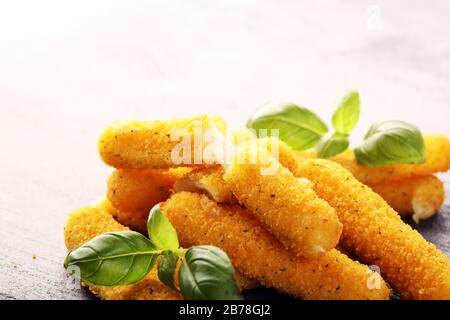 Panierte Mozzarella-Käsestäbchen mit Basilikum auf dem Tisch Stockfoto