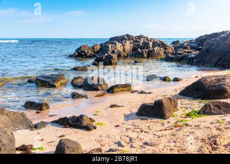 Felsen am Meeresstrand am Morgen. Ruhiges, sonniges Wetter. Abgeschiedener Ort. Flauschige Wolken über dem Horizont. Stockfoto