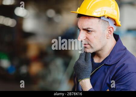 Europäischer russischer Arbeiter denkt an einen gutaussehenden Fabrikmann, der Schutzanzug und Handrille trägt. Stockfoto