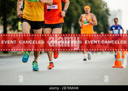 Warnungsband Veranstaltung abgebrochen Coronavirus im Hintergrund Athleten Läuferinnen laufen Stadtmarathon Stockfoto