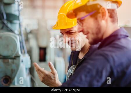 Zufriedene Arbeiter, lächelnder Techniker, Ingenieur arbeitet gerne mit Kollegen zusammen. Stockfoto