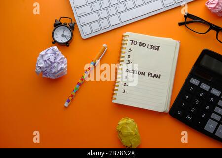 Draufsicht der to DO-Liste mit Taschenrechner, Uhr und Tastatur auf orangefarbenem Hintergrund Stockfoto