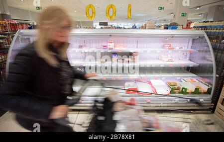 Berlin, Deutschland. März 2020. In einem Supermarkt in Berlin-Wilmersdorf läuft eine Frau an einer teilweise leeren Kühltheke vorbei. (Wischeffekt durch längere Belichtungszeit) Credit: Christoph Soeder / dpa / Alamy Live News Stockfoto