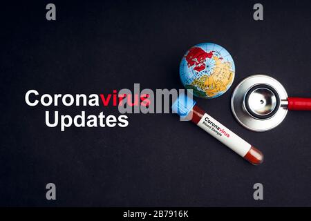COVID-19 AKTUALISIERT Text mit Stethoskop, Weltkugel und Blutprobenvakuumschlauch auf schwarzem Hintergrund. Covid oder Coronavirus Konzept Stockfoto