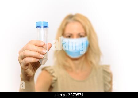 Blonde Forscherin mit einer medizinischen Maske, die ein Reagenzglas für Labortests oder Experimente hält. Konzept der wissenschaftlichen Forschung, Virus-Test Stockfoto