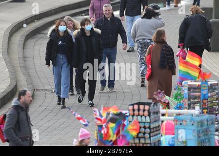 Menschen, die Gesichtsmasken tragen, spazieren auf der Promenade in Brighton. Stockfoto