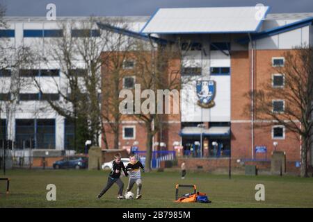 (Die Erlaubnis wurde erteilt, aber die Namen wurden nicht veröffentlicht) Zwei Jungen spielen Fußball in Hillsborough Park außerhalb von Hillsborough, dem Sitz des Sheffield Wednesday Football Club, nachdem sie gestern angekündigt haben, dass die englische Football League alle Spiele bis Freitag, den 3. April 2020, ausgesetzt hat. Stockfoto