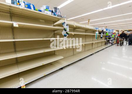 Käufer, die nach Wasser in Flaschen suchen, aber in einem Supermarkt leere Regale finden, da Coronavirus Angst und Panik horizontal verursacht Stockfoto