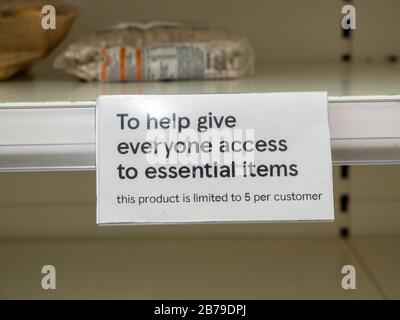 Ein Zeichen, das den Verkauf von Artikeln in leeren Regalen im Tesco Supermarkt in Cambridgeshire UK einschränkt, während Menschen als Reaktion auf das Coronavirus in Panik Lebensmittel kaufen. Stockfoto