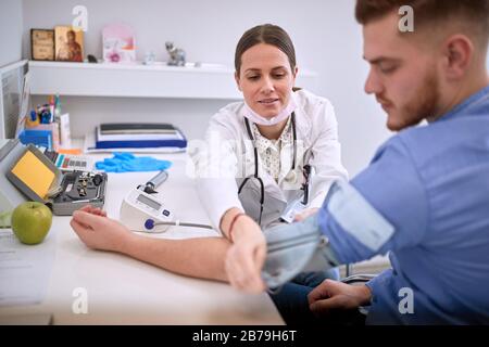 Hausärztin legt Manschette auf den Arm des Patienten Stockfoto