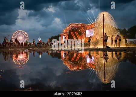 KOSTRZYN NAD ODRA, POLEN - 3. AUGUST 2017: Festival Przystanek Woodstock - Fans baden im Schlamm vor der Bühne mit Reflexion über das Wasser. Stockfoto