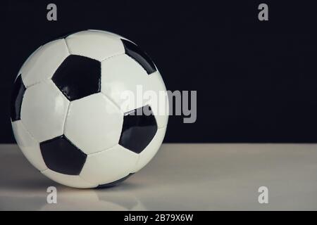 Klassischer Fußball-Ball, schwarz-weiß, isoliert auf dem Tisch mit Kopierraum. Echtes, traditionelles Fußballsymbol. Stockfoto