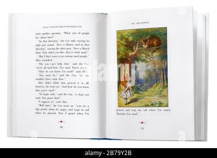 Alice im Wunderland von Lewis Carroll, offen bei einer Illustration von Alice und der Cheshire Cat. Stockfoto