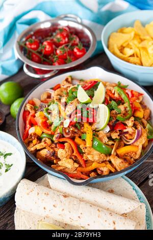 Hühnerfajita in einer rustikalen Pfanne mit hausgemachten Dips Stockfoto