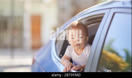 Ein kleines Mädchen fährt mit dem Auto und schaut aus dem Fenster Stockfoto