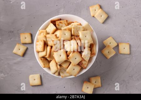 Cracker Plätzchen in einer weißen Keramikschale auf grauem Hintergrund, Draufsicht Stockfoto