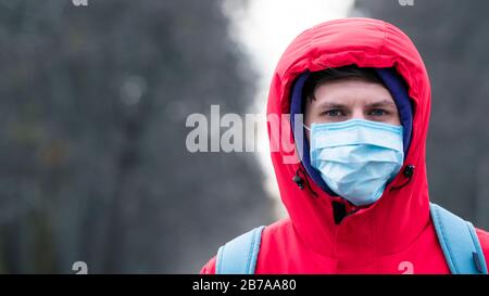 Nahaufnahme Portrait junger europäer Mann in schützender, medizinischer Gesichtsmaske, die draußen spazieren geht. Neues Coronavirus (COVID-19). Konzept der Gesundheitsversorgung Stockfoto