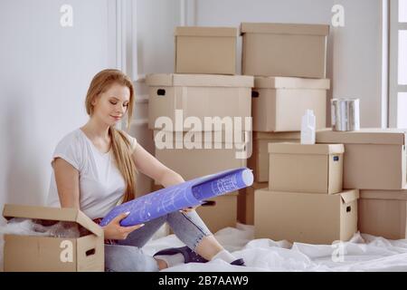 Mädchen sitzt zwischen Boxen macht Marken auf dem Plan der Wohnung Stockfoto