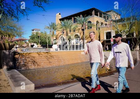 Zwei tausende Männer spazieren vor dem Wasserfall in Southbridge im Einkaufsviertel Scottsdale, AZ, USA Stockfoto