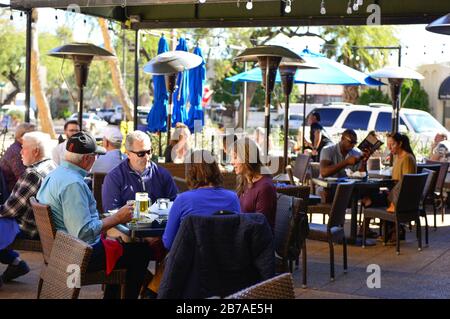 Gruppen von Leuten, die an Tischen mit Terrasse außerhalb des Restaurants im Southbridge-Gebiet in Scottsdale, AZ, USA trinken und essen Stockfoto