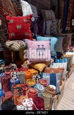 Lebhafte Stoffe, Textilien, Teppiche und Kissen zum Verkauf in den sonnigen Suken von Essaouira, Marokko Stockfoto