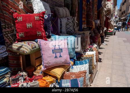 Lebhafte Stoffe, Textilien, Teppiche und Kissen zum Verkauf in den sonnigen Suken von Essaouira, Marokko Stockfoto