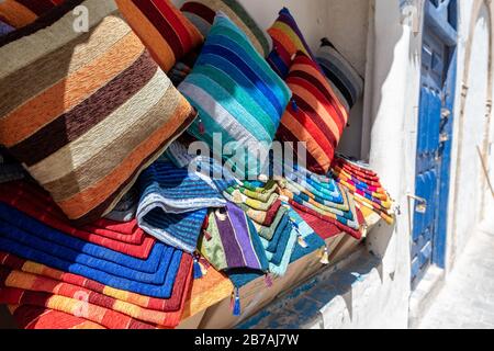 Lebhafte Stoffe, Textilien, Teppiche und Kissen zum Verkauf in den sonnigen Suken von Essaouira, Marokko Stockfoto