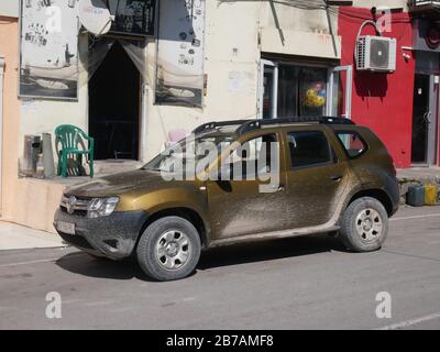 Schmutzige dacia Duster-suv nach der Straßenfahrt in Georgia Country mit Bauhintergrund Stockfoto