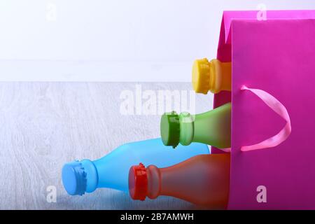 Energy trinkt Behälter mit verschiedenen Geschmacksrichtungen. Satz Flaschen in verschiedenen Farben in pinkfarbener Verpackung. Einkaufstasche mit bunten alkoholfreien Getränken auf grauem Hintergrund. Farbauswahl und Container-Konzept Stockfoto