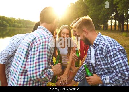 Junge Leute trinken, essen und stinken Gläser bei einem Picknick Stockfoto