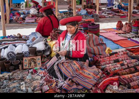 Cuzco, Peru: Quechua-Frauen in traditioneller indigener Kleidung auf dem Markt, die bunte Textilwaren verkaufen, die lokale Souvenirs für Handwerke anstellen Stockfoto