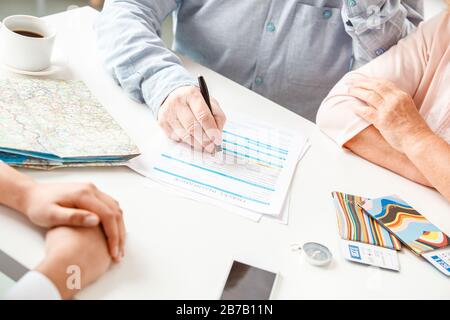 Afrikanische Abstiegsfrau Reisebüro im Büro mit Senioren-Paar, das Versicherungsformular erfüllt, konzentrierte sich auf die Nahaufnahme Stockfoto