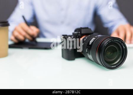 Hände nah oben, Seitenansicht. Die Arbeit eines Grafikdesigners. Fotoausrüstung auf dem Tisch. Retuschieren von Fotos Stockfoto