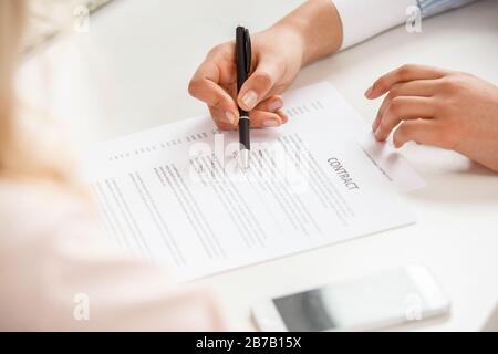 Afrikanischer Absteiger, weiblicher Reisevermittler im Büro, bei dem eine ältere Frau einen Vertrag über die Vertragsabsprache mit den Teilnahmebedingungen abschließt Stockfoto