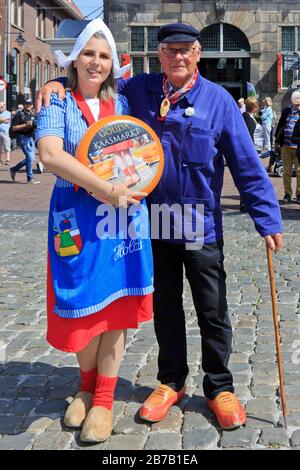 Mädchen in traditioneller holländischer Kleidung mit einer Gouda-Käsekugel und einem Käsebauer auf dem Käsemarkt in Gouda (Südholland), Niederlande Stockfoto