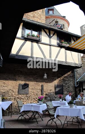 Burghotel Schloss auf Schönburg (auf Schönburg) in Oberwesel, Deutschland. Schlossterrasse im Innenhof mit geteiltem Fachwerk. Stockfoto