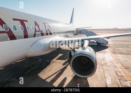 Der Blick über einen Flügel eines Airbus A320 von Qatar Airways und eine Rampe an einem heißen Sommertag auf dem Hamad International Airport, Doha Stockfoto