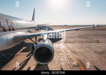 Der Blick über einen Flügel eines Airbus A320 von Qatar Airways und eine Rampe an einem heißen Sommertag auf dem Hamad International Airport, Doha Stockfoto