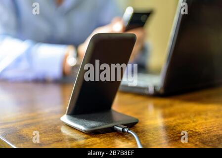 Schnurloses Telefon Ladestation über dem Mann, der das Smartphone zu Hause hält Stockfoto