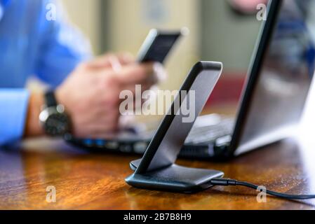 Schnurloses Telefon Ladestation über dem Mann, der das Smartphone zu Hause hält Stockfoto