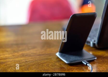 Ladestation für drahtlose Telefone über Laptop auf dem Schreibtisch im Büro Stockfoto